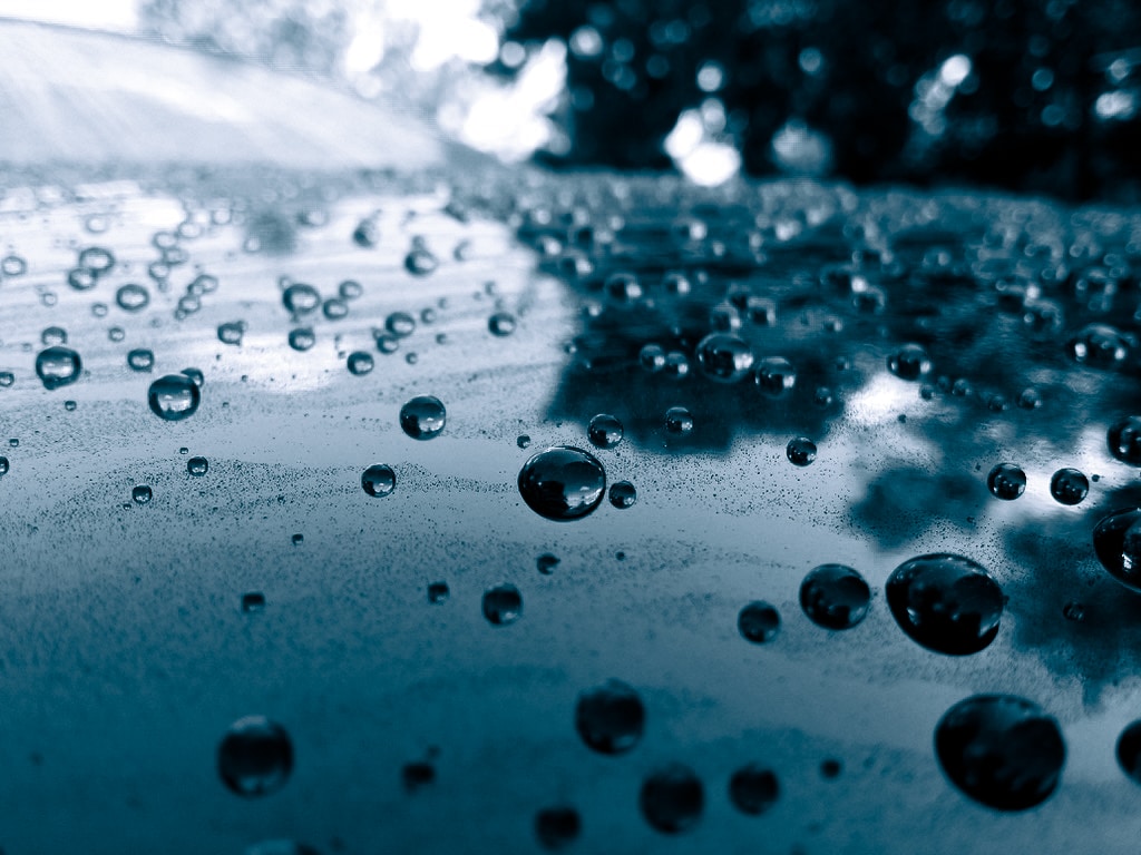 Water droplets beading on a reflective vehicle surface